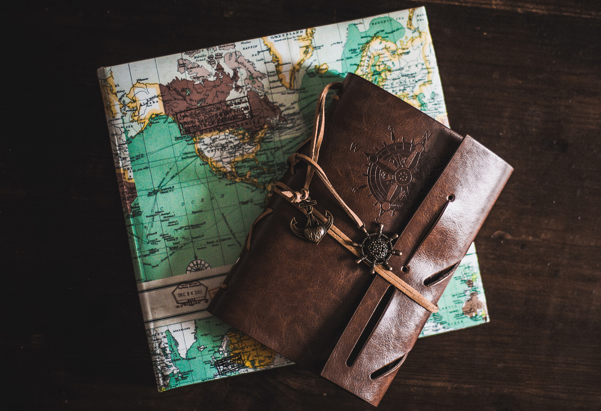 a gift wrapped in a map-print wrapping paper and a leather-bound journal with a compass on the cover