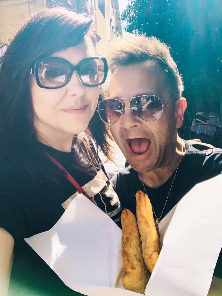 Andie stands next to Stephen as he is about to bite into a portafoglio pizza in Naples, Italy