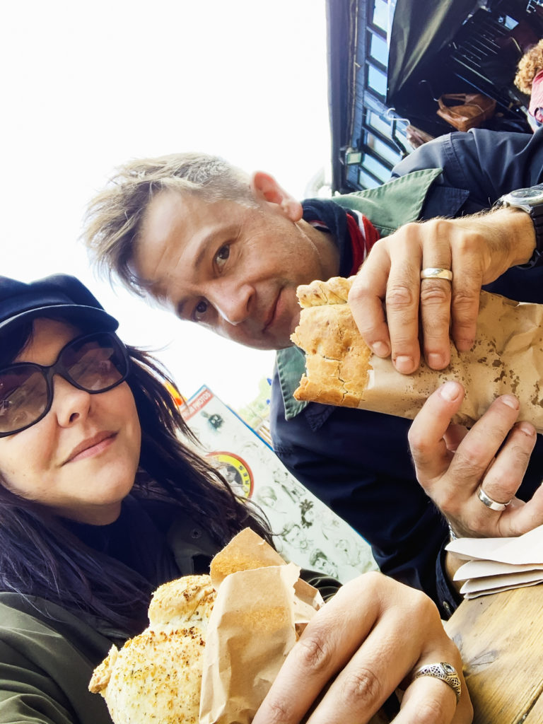 a woman and man hold their pasties, which they are eating. 48 hours in London