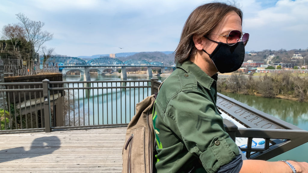 a man looks out over a river with a bridge in the background