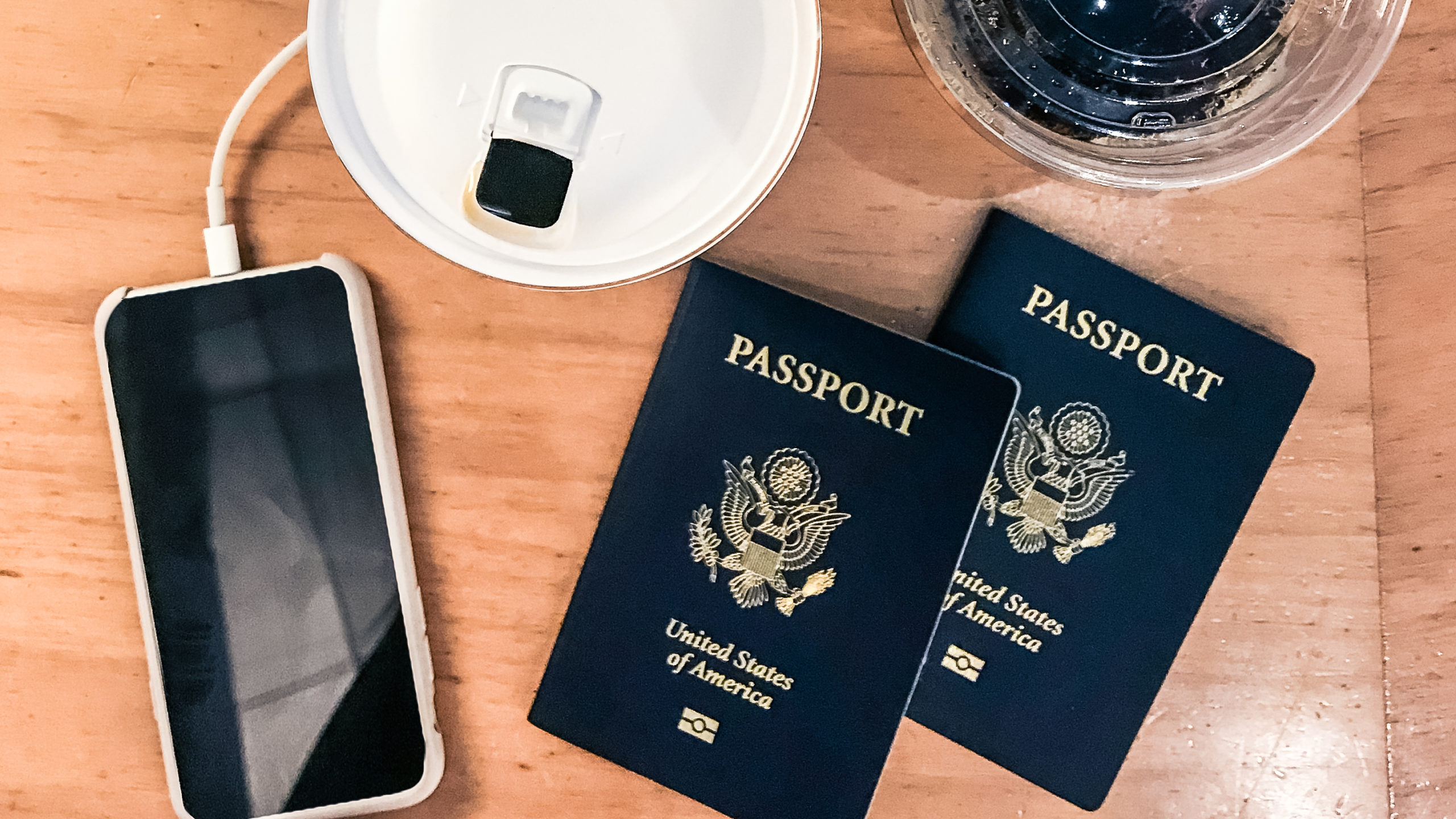 passports, mobile phone, and coffees on a table