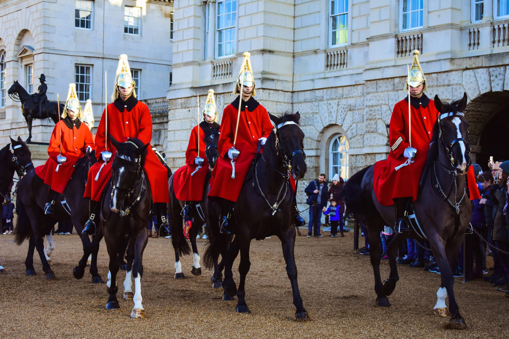 Palace guards ride on horses in front of Buckingham Palace