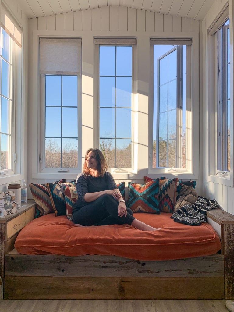 a woman curls up on the couch in the living room of a tiny home
