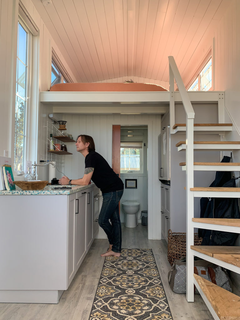 a man leans against the kitchen counter in a tiny house