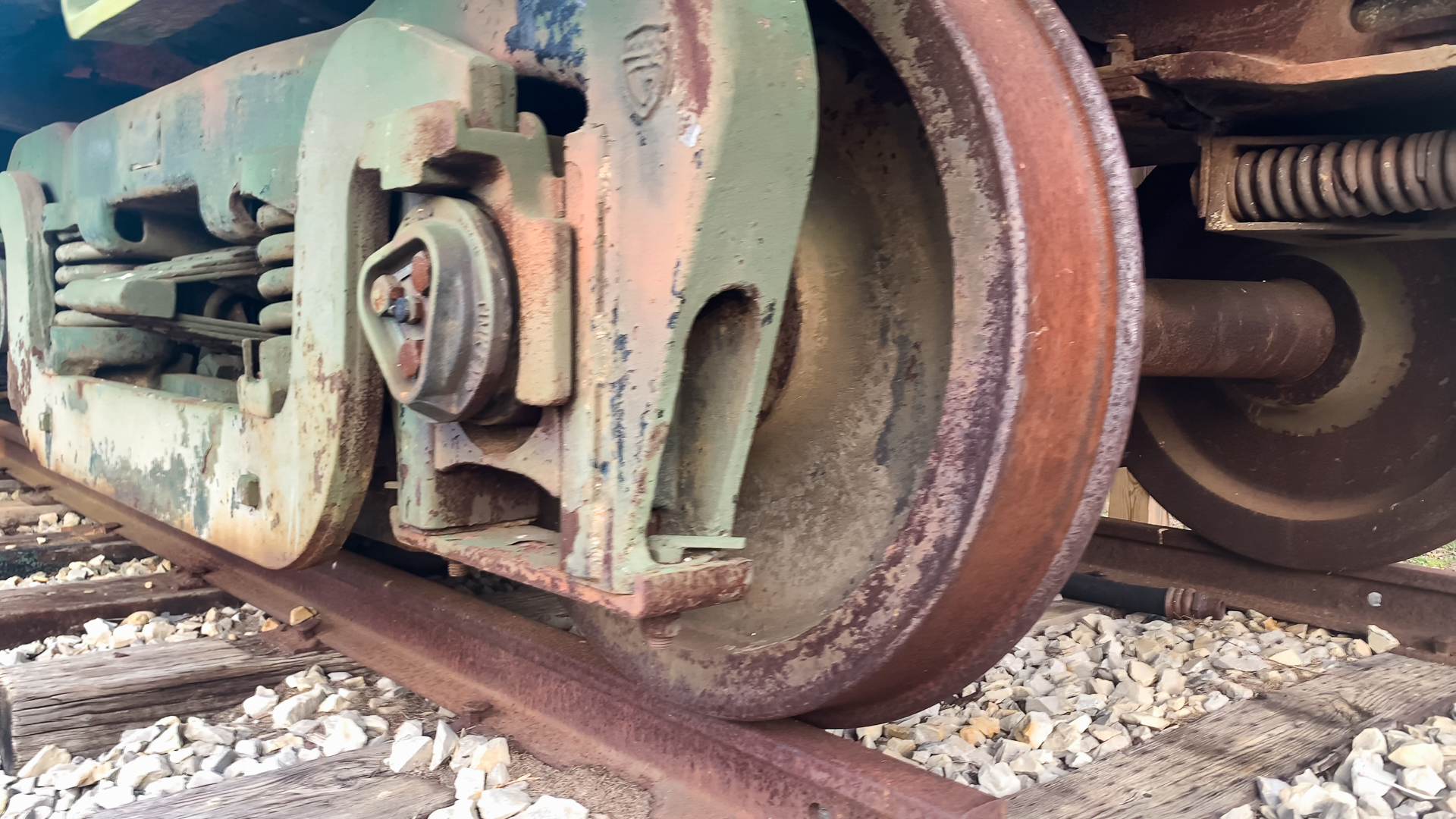 close up of the rusted wheel of an old train car on a train track