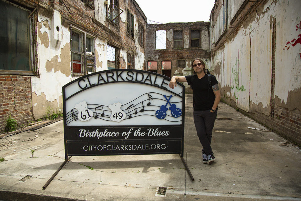 Stephen stands beside a sign that reads "Clarksdale, Mississippi, birthplace of the blues"