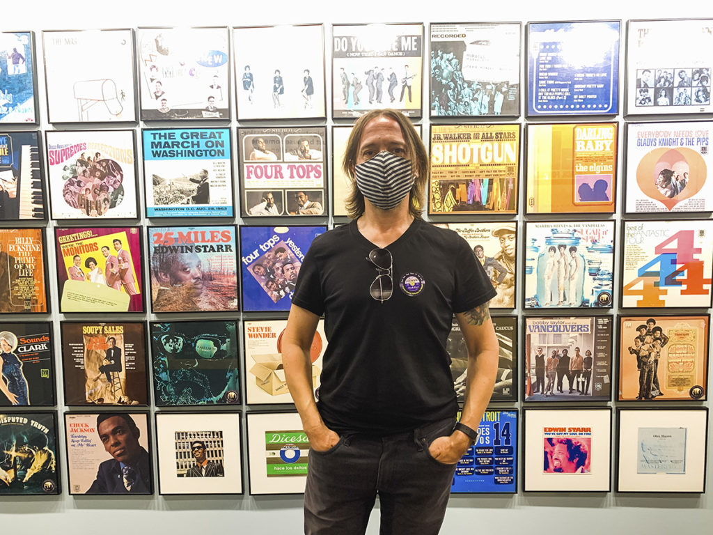 Stephen stands in front of a wall of album covers
