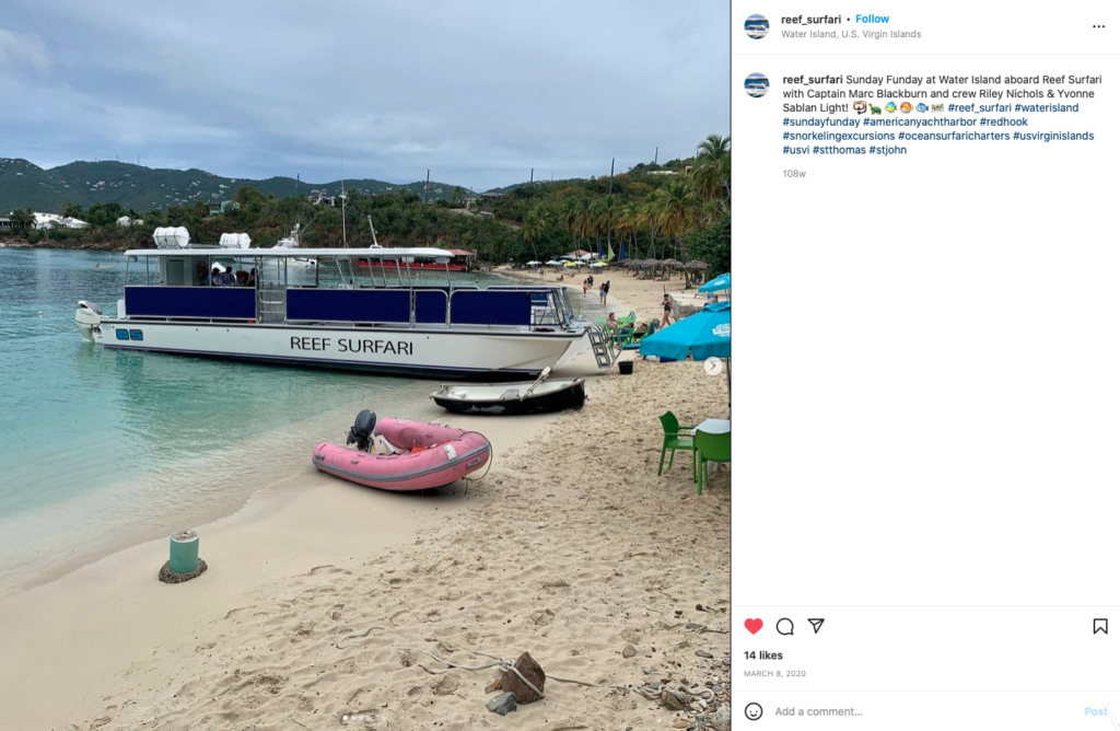 Reef Surfari snorkeling excursion boat ashore on the white sand beach in U.S. Virgin Islands. various rafts and tables and chairs with umbrellas on beach