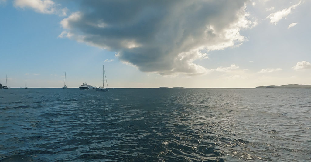 Beautiful view from the water in U.S. Virgin Islands National Park. Clouds, boats, sun, and horizon.