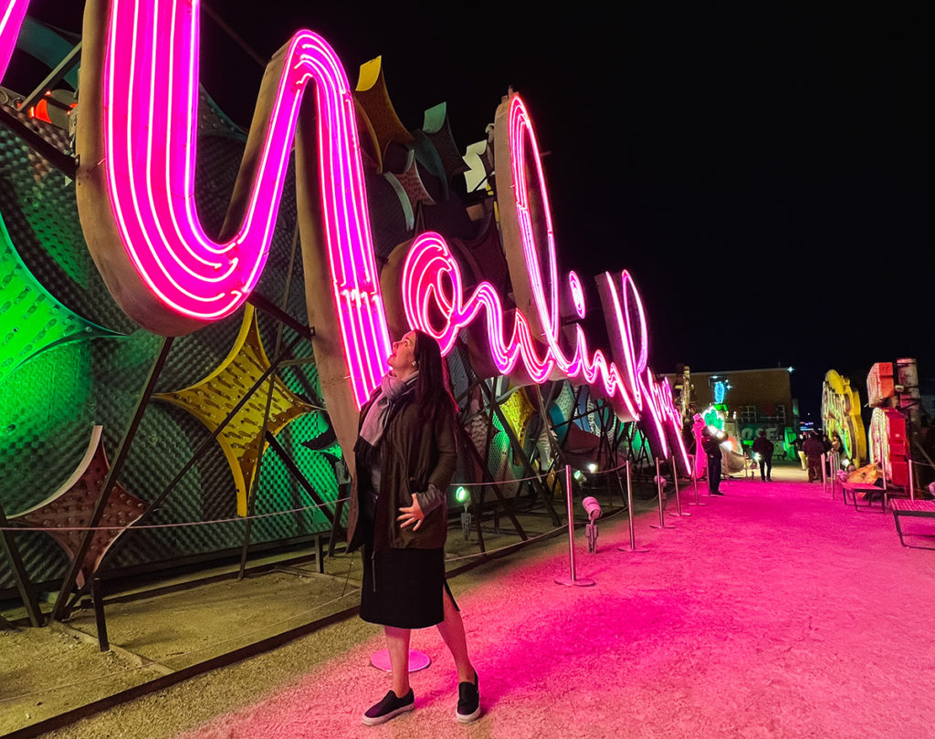 Woman standing in front of the massive, fully refurbished and lighted Moulin Rouge sign at the Neon Museum in Las Vegas