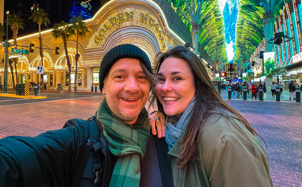 man and woman posing at Fremont Street in Las Vegas, with The Golden Nugget and the Fremont Street Experience behind them