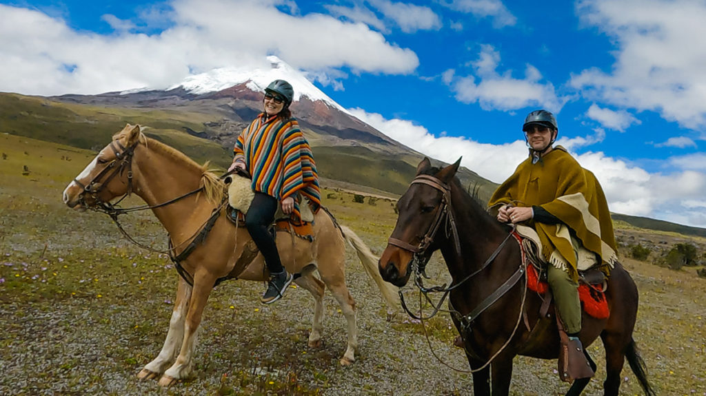 man and woman horseback, posing in front of Cotopaxi - Ecuador's second-largest active volcano. Cotopaxi National Park. the trip was booked through an eco-conscious, local travel agent,
