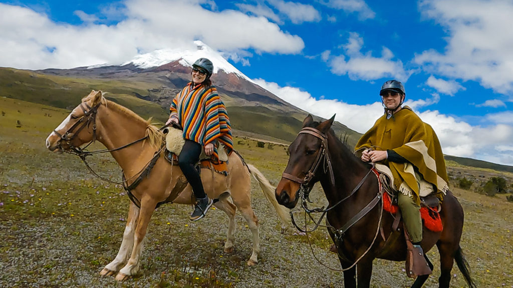 man and woman on horseback at Cotopaxi National Park, one of the high altitude destinations in Ecuador. snow-capped Cotopaxi volcano is in the backgrioud