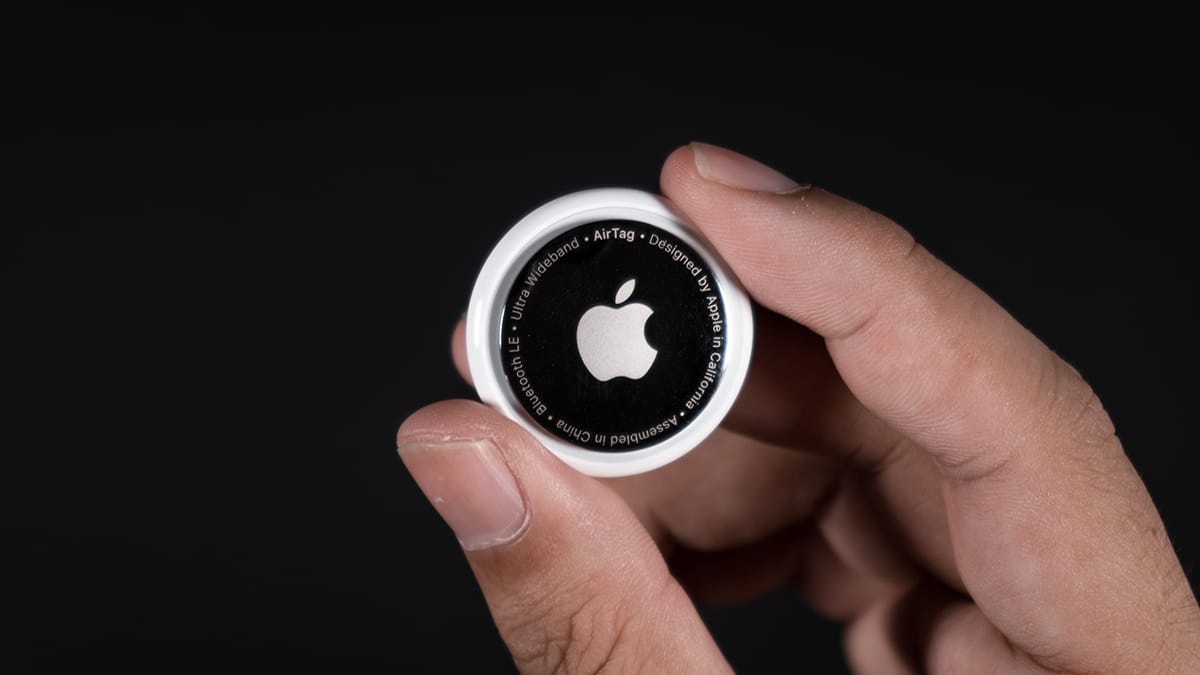 person's hand holding black and white Apple AirTag