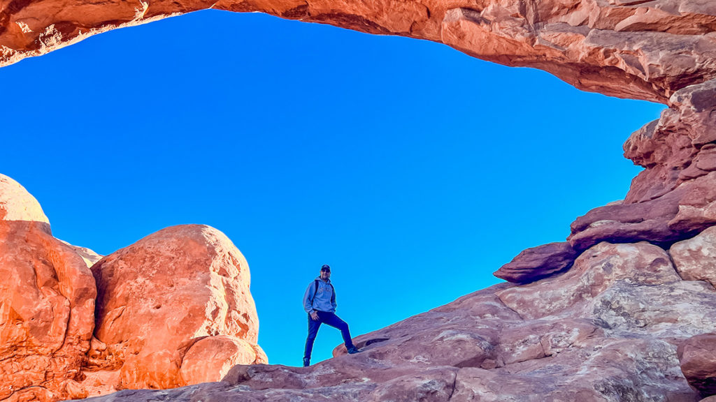 A man standing proudly inside one of the "windows" in Arches National Park in Utah.