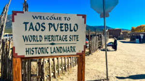 sign near entrance to Taos Pueblo reading "Welcome to Taos Pueblo World Heritage Site Historic Landmark"