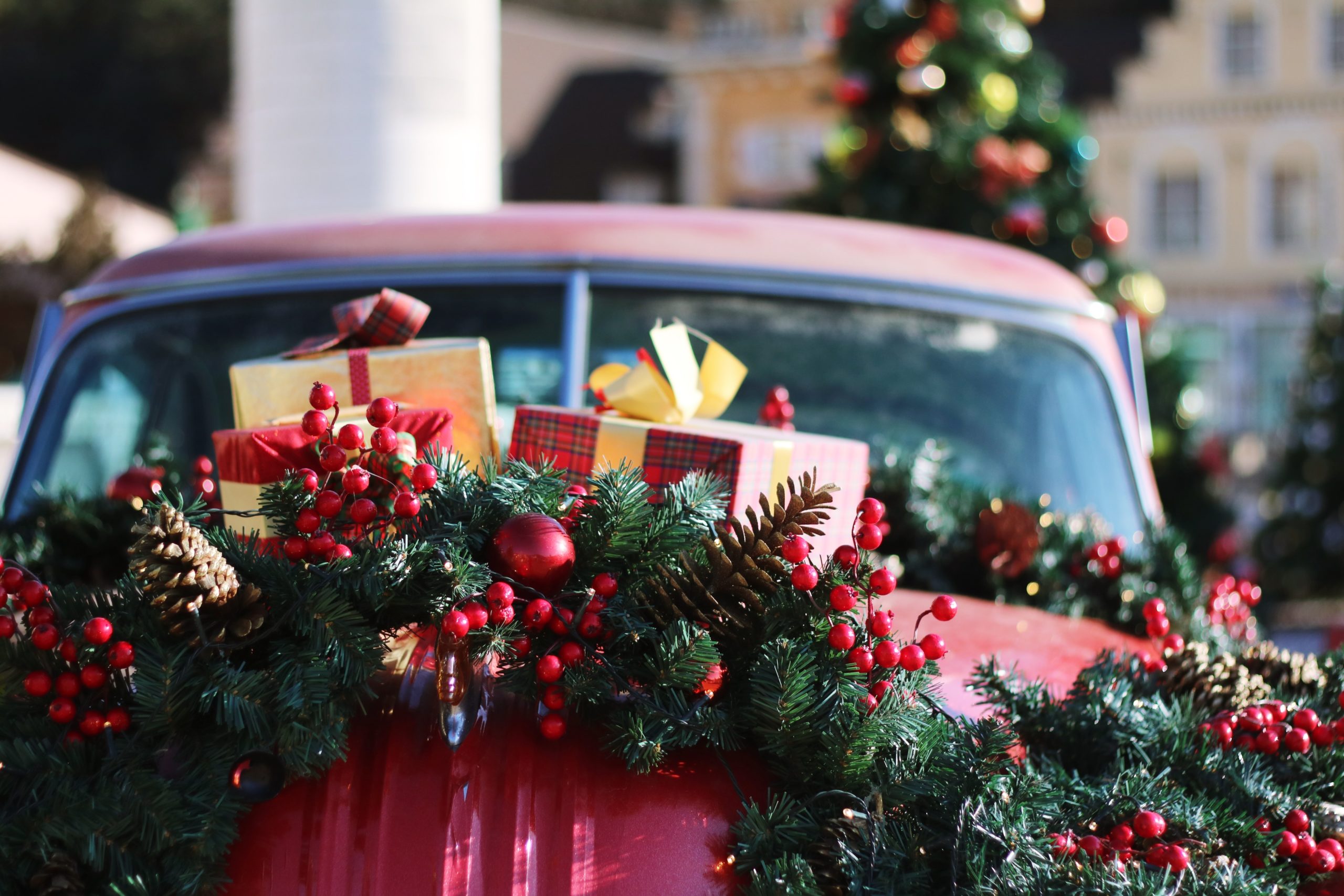 a green and red wreath with small presents on a red vintage car